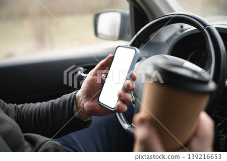 Driver Holding Smartphone And Coffee Cup While Driving Driver Holding Smartphone And Coffee Cup While Driving 139216653