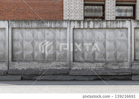 Brick wall of an industrial building is behind a weathered concrete fence Brick wall of an industrial building is behind a weathered concrete fence 139216691