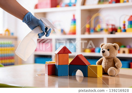 Gloved hand spraying disinfectant on children's toys and building blocks in a classroom Gloved hand spraying disinfectant on children's toys and building blocks in a classroom 139216928