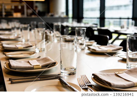 Elegant restaurant table setting with glassware, napkins, and cutlery ready for guests 139216941