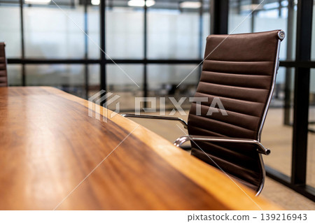 Modern executive office chair and polished wood conference table in a bright meeting room 139216943