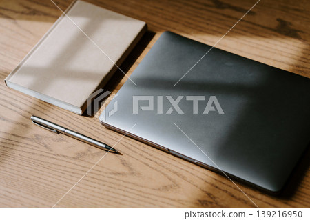 Minimalist desk setup with closed laptop, notebook, and pen on a wooden surface Minimalist desk setup with closed laptop, notebook, and pen on a wooden surface 139216950