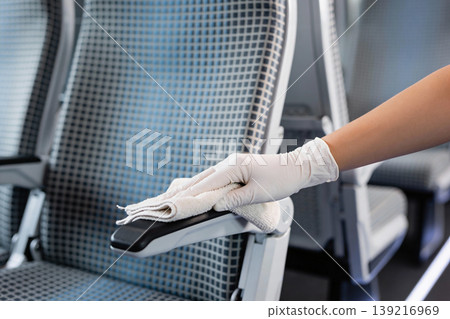 Hand in glove wiping down armrest of airplane seat with cloth for hygiene and cleanliness Hand in glove wiping down armrest of airplane seat with cloth for hygiene and cleanliness 139216969