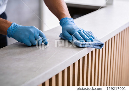 Person wearing blue gloves wipes down a counter with a microfiber cloth Person wearing blue gloves wipes down a counter with a microfiber cloth 139217001