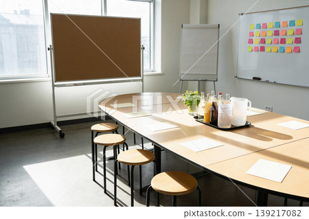 Modern meeting room setup with a large oval table, chairs, and presentation boards 139217082