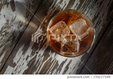 Refreshing drink with ice cubes on rustic wooden table during a warm evening 139217399