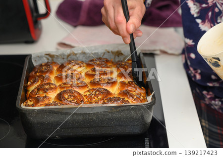 Freshly baked sweet rolls being glazed in a cozy kitchen filled with warmth and delightful aromas 139217423