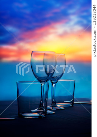 Dish of cups and crystal glasses on sea sunset Dish of cups and crystal glasses on sea sunset 139218044