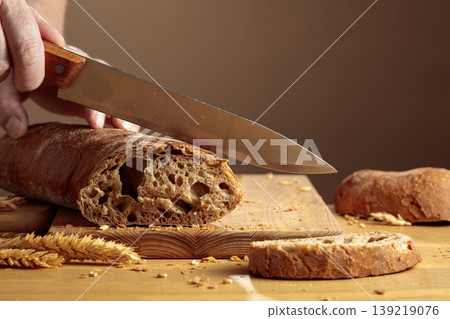 The chef is slicing freshly baked bread. 139219076