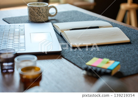 Laptop and open notebook on home office desk with coffee mug Laptop and open notebook on home office desk with coffee mug 139219354
