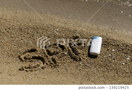 SPF message and sunscreen bottle on sandy beach near sparkling water SPF message and sunscreen bottle on sandy beach near sparkling water 139219425