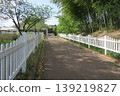 A walkway surrounded by trees and a white fence 139219827
