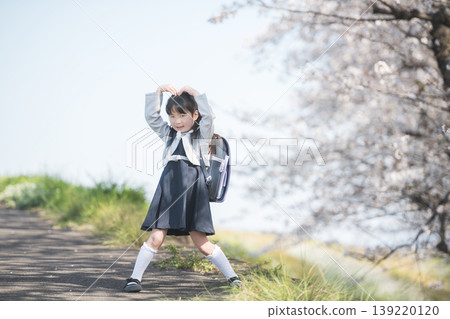 A first-grade girl in her school backpack poses in front of a row of cherry trees in full bloom. A first-grade girl in her school backpack poses in front of a row of cherry trees in full bloom. 139220120