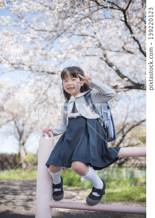一位剛入學的小女孩在櫻花盛開的公園裡微笑。 一位剛入學的小女孩在櫻花盛開的公園裡微笑。 139220123