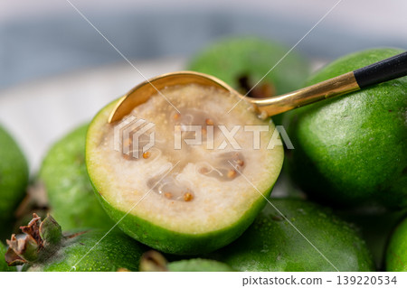 Extreme close-up of a feijoa with a golden spoon 139220534