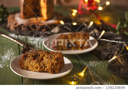 Two Slices of Panettone on Plates with Festive Holiday Decorations Two Slices of Panettone on Plates with Festive Holiday Decorations 139220699