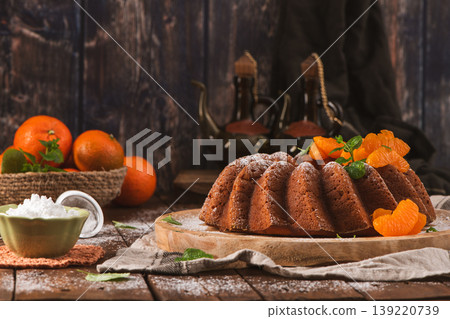 Glazed Tangerine Bundt Cake on Wooden Board with Citrus and Powdered Sugar 139220739