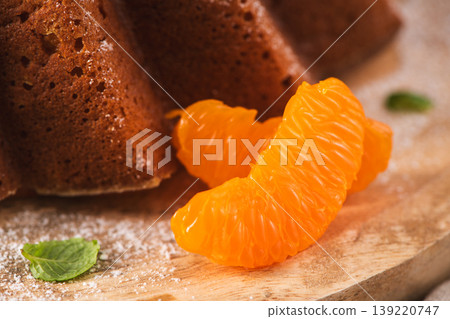 Close-up of Fresh Orange Segments Beside a Glazed Bundt Cake 139220747