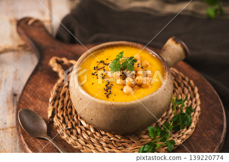 Creamy Pumpkin Soup Topped with Chickpeas and Black Sesame Seeds in a Rustic Ceramic Bowl 139220774