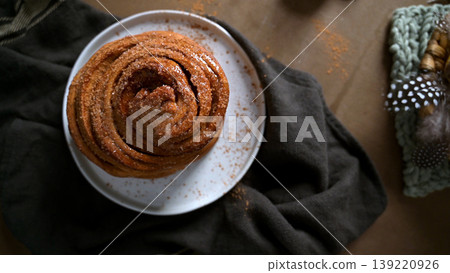 Top View of Freshly Baked Cinnamon Roll on White Plate with Dark Linen Top View of Freshly Baked Cinnamon Roll on White Plate with Dark Linen 139220926