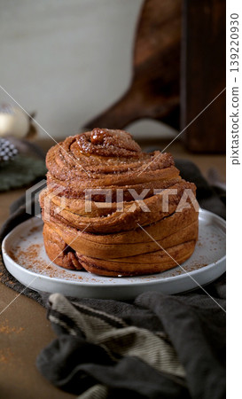Artisanal Cinnamon Bun on White Plate with Dark Linen Artisanal Cinnamon Bun on White Plate with Dark Linen 139220930