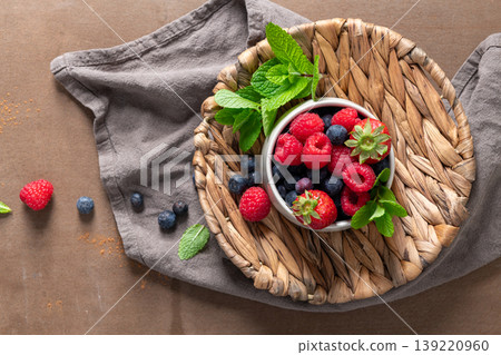 Top View of Fresh Mixed Berries in Bowl with Mint on Rustic Woven Tray Top View of Fresh Mixed Berries in Bowl with Mint on Rustic Woven Tray 139220960