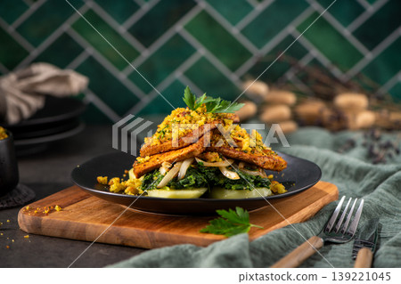 Gourmet Breaded Tofu Steaks with Sauteed Greens and Potatoes on a Rustic Wooden Board Gourmet Breaded Tofu Steaks with Sauteed Greens and Potatoes on a Rustic Wooden Board 139221045