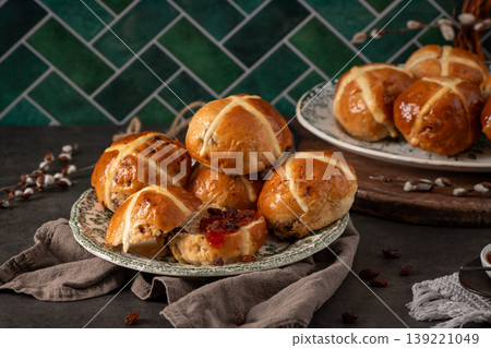 Easter Hot Cross Buns Stacked on Vintage Plates against Green Tile Background 139221049