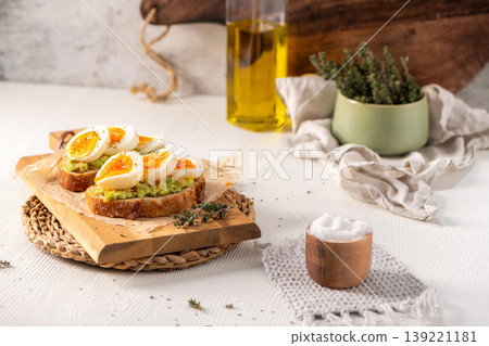 Sourdough Toast Topped with Smashed Avocado and Soft Boiled Eggs on a Wooden Board Sourdough Toast Topped with Smashed Avocado and Soft Boiled Eggs on a Wooden Board 139221181