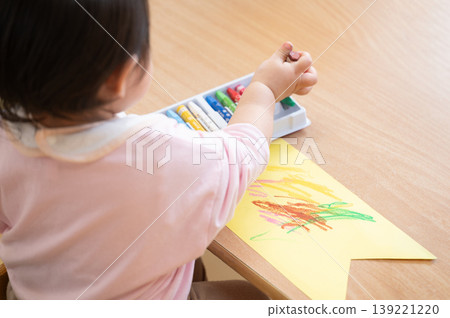 A scene from a nursery school where toddlers choose crayons and enjoy drawing time. A scene from a nursery school where toddlers choose crayons and enjoy drawing time. 139221220