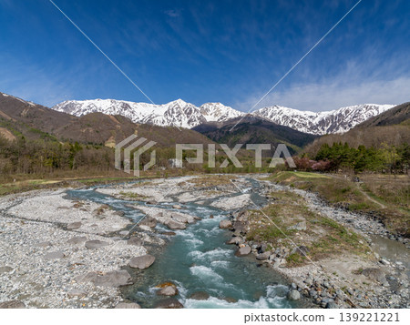 A river flowing with snowmelt water and the magnificent scenery of the Hakuba Three Peaks. 139221221