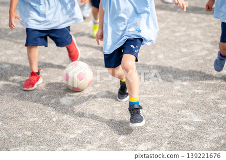 A lively scene of children enjoying playing with a ball in the schoolyard. A lively scene of children enjoying playing with a ball in the schoolyard. 139221676