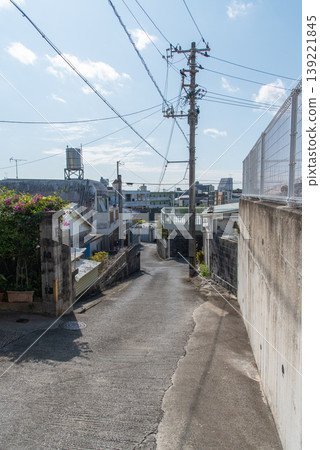 A narrow alleyway on a clear day, lined with utility poles and power lines. A narrow alleyway on a clear day, lined with utility poles and power lines. 139221845