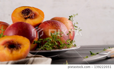 Fresh Ripe Nectarines and Sliced Fruit with Green Herbs on a Rustic Table Fresh Ripe Nectarines and Sliced Fruit with Green Herbs on a Rustic Table 139222031