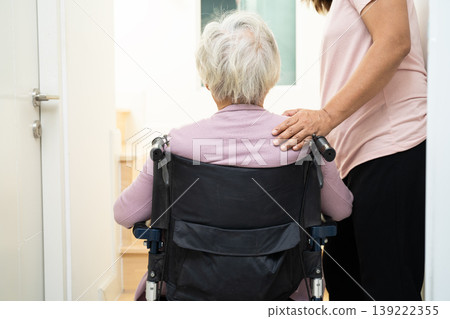 Caregiver help asian elderly woman sitting wheelchair support up the stairs in home. Caregiver help asian elderly woman sitting wheelchair support up the stairs in home. 139222355