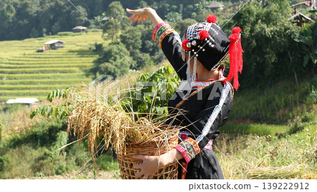 Ethnic tribal woman in traditional dress harvesting rice in terraced fields, celebrating rural lifestyle, cultural heritage, and sustainable farming in mountain village Ethnic tribal woman in traditional dress harvesting rice in terraced fields, celebrating rural lifestyle, cultural heritage, and sustainable farming in mountain village 139222912