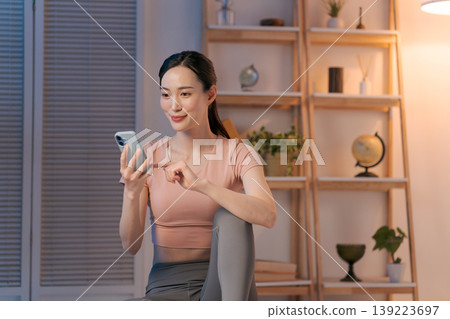 A woman in yoga wear looking at her smartphone A woman in yoga wear looking at her smartphone 139223697