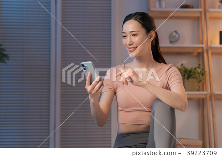 A woman in yoga wear looking at her smartphone A woman in yoga wear looking at her smartphone 139223709