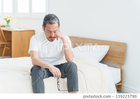A tired-looking middle-aged man resting in bed. 139223790