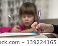 Portrait of cute pretty little serious child girl drawing with pencil on paper on blurred background. Art education, creativity, doing homework and children activities concept. 139224165