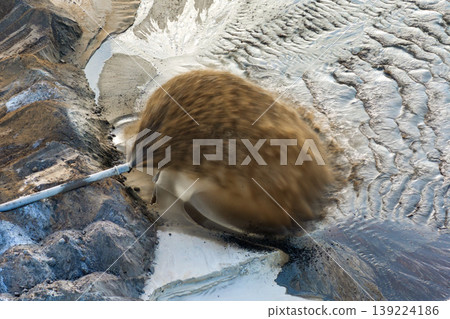 Phosphate mining site in Florida with large pipe ejecting water and sand slurry during mineral extraction process. 139224186