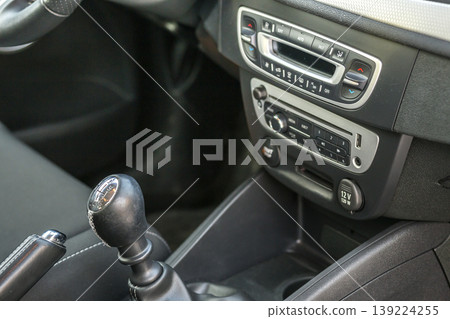 Luxurious car black leather interior. Close-up detail of handbrake manual brake and gearshift stick on blurred dashboard background. Transportation, design, modern technology concept. Luxurious car black leather interior. Close-up detail of handbrake manual brake and gearshift stick on blurred dashboard background. Transportation, design, modern technology concept. 139224255