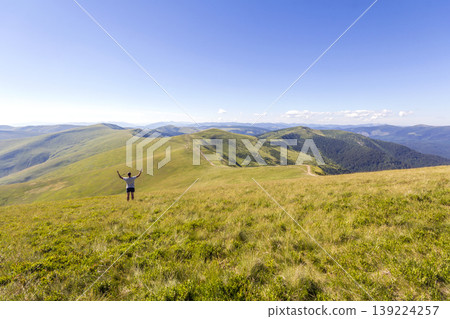 Lonely hiker standing in mountains. Tourist man enjoy mountain view Lonely hiker standing in mountains. Tourist man enjoy mountain view 139224257