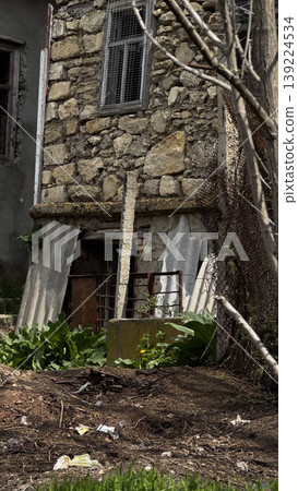 A weathered stone building surrounded by nature and litter. A weathered stone building surrounded by nature and litter. 139224534