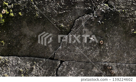Close-up of a weathered wall featuring cracks and moss. Close-up of a weathered wall featuring cracks and moss. 139224602