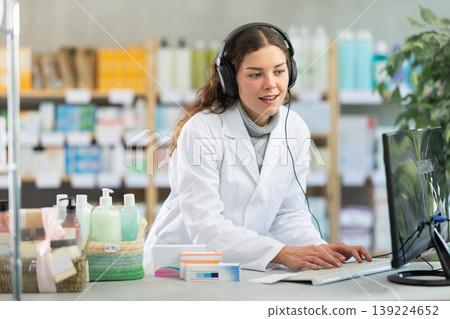 Female pharmacist in headphones working at computer Female pharmacist in headphones working at computer 139224652