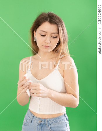 Sad young woman in casual clothes standing on chromakey background Sad young woman in casual clothes standing on chromakey background 139224662