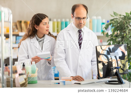 Experienced pharmacist and his assistant check data on medical drugs on Internet Experienced pharmacist and his assistant check data on medical drugs on Internet 139224684