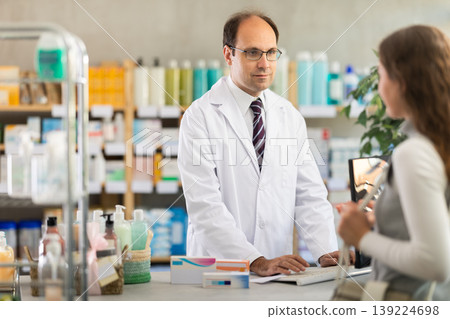 Pharmacist searches for medicine on computer for female buyer Pharmacist searches for medicine on computer for female buyer 139224698
