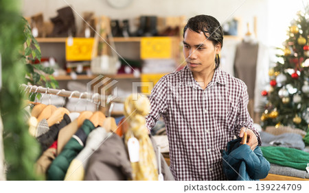 In chain shop, Indonesian man choose down jacket or rain coat, X mas shopping In chain shop, Indonesian man choose down jacket or rain coat, X mas shopping 139224709